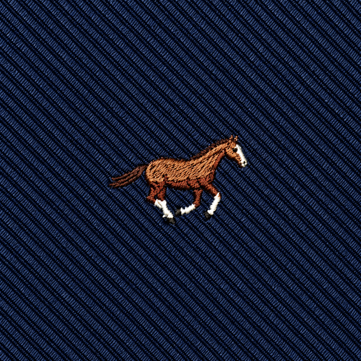 Featuring an embroidered brown horse with white markings set against a dark blue, diagonally striped fabric, the Thoroughbred Horse Skinny Tie is an elegant choice that makes a perfect gift for horse lovers and brings refined style to any collection.