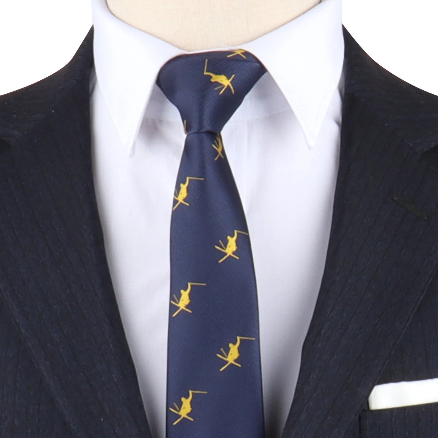 Close-up of a person wearing a dark pinstripe suit, white shirt, and a navy tie with a yellow pattern featuring small figures of men playing polo. A white pocket square is partially visible in the breast pocket. The tie adds a touch of Ski Tie to the ensemble.