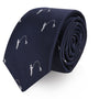 A Fisherman Skinny Tie, dark blue with a small repetitive pattern of white fishing figures, effortlessly rolled up on a white background, waiting to reel in compliments.