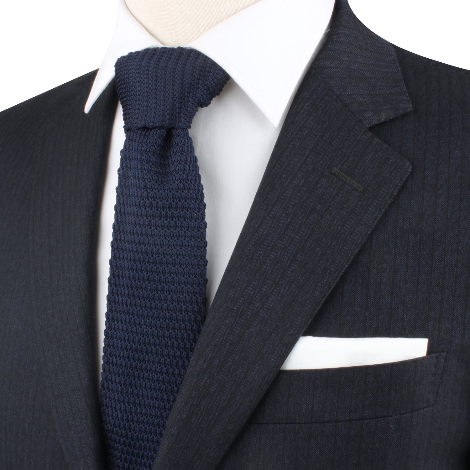 Close-up of a person wearing a dark pinstripe suit, a white dress shirt, and a Navy Knitted Skinny Tie that evokes the elegance of deep-sea hues, complemented by a white pocket square.