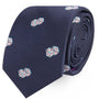 The Dice Skinny Tie is a rolled dark blue tie featuring a chic pattern of small white dice, ideal for adding a touch of luck to any outfit.