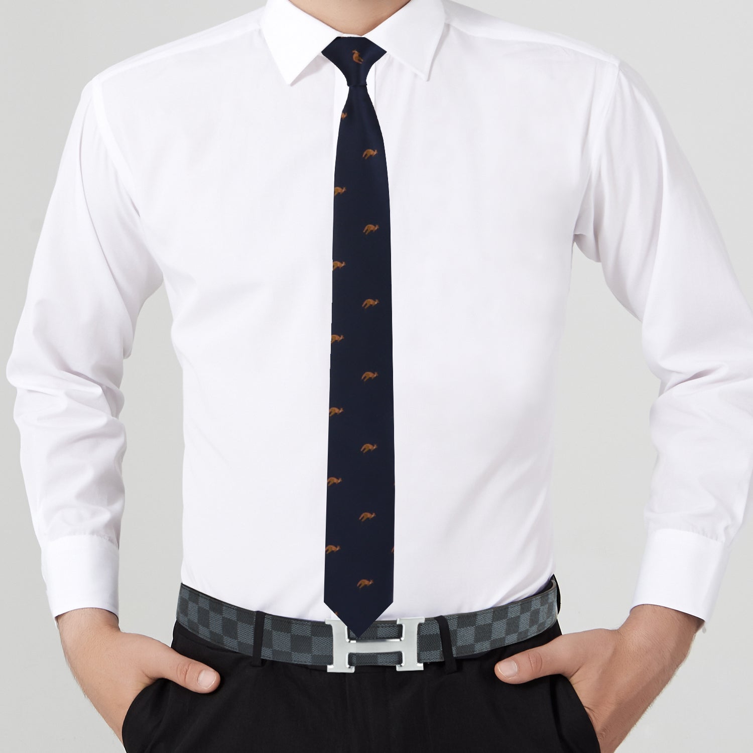 A person in a white dress shirt, the Kangaroo Skinny Tie, and black pants with hands in pockets exudes unmatched elegance, accessorized with a checkered belt featuring a metallic buckle.