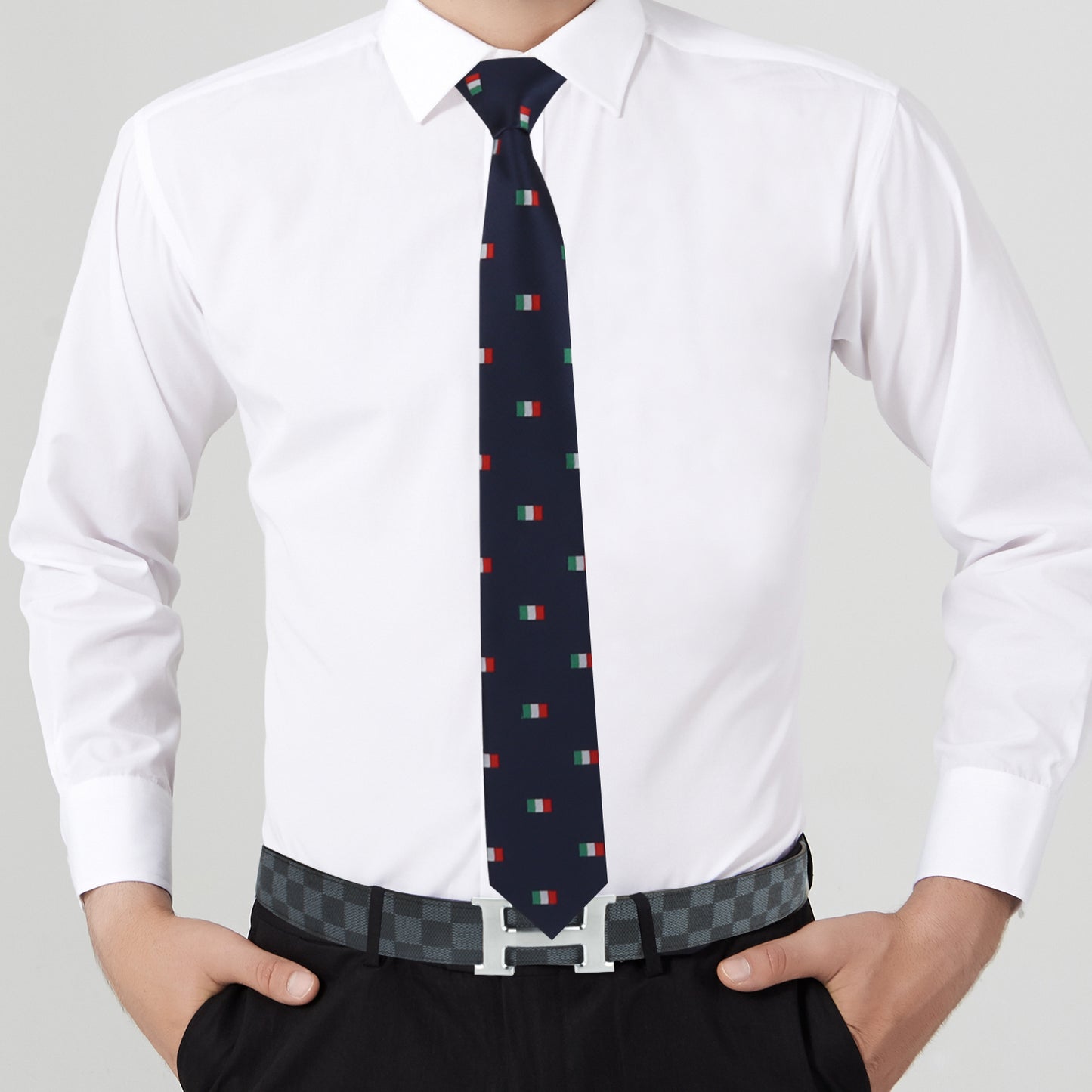 A person exudes elegance in a white dress shirt, an Italian Mexican Flag Skinny Tie, and black pants accented by a patterned belt — a stylish fusion of fashion and cultural expression.