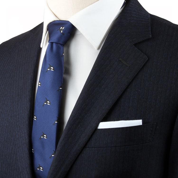 A person wearing a dark pinstripe suit with a white dress shirt, Killer Whale Skinny Tie, and a white pocket square exudes contemporary elegance.