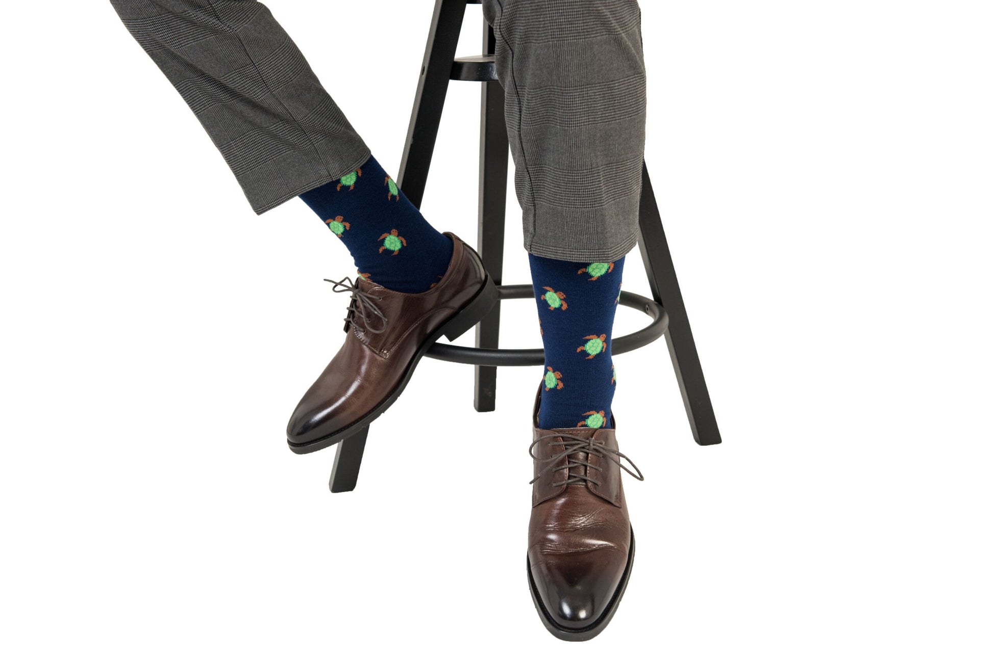 A man sitting on a stool wearing a pair of Green Turtle Socks.