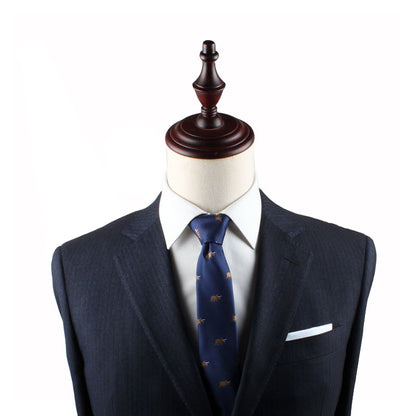 A mannequin dressed in a dark suit with a Triceratops Skinny Tie featuring a pattern, white dress shirt, and a white pocket square exudes modern elegance against a plain white background.