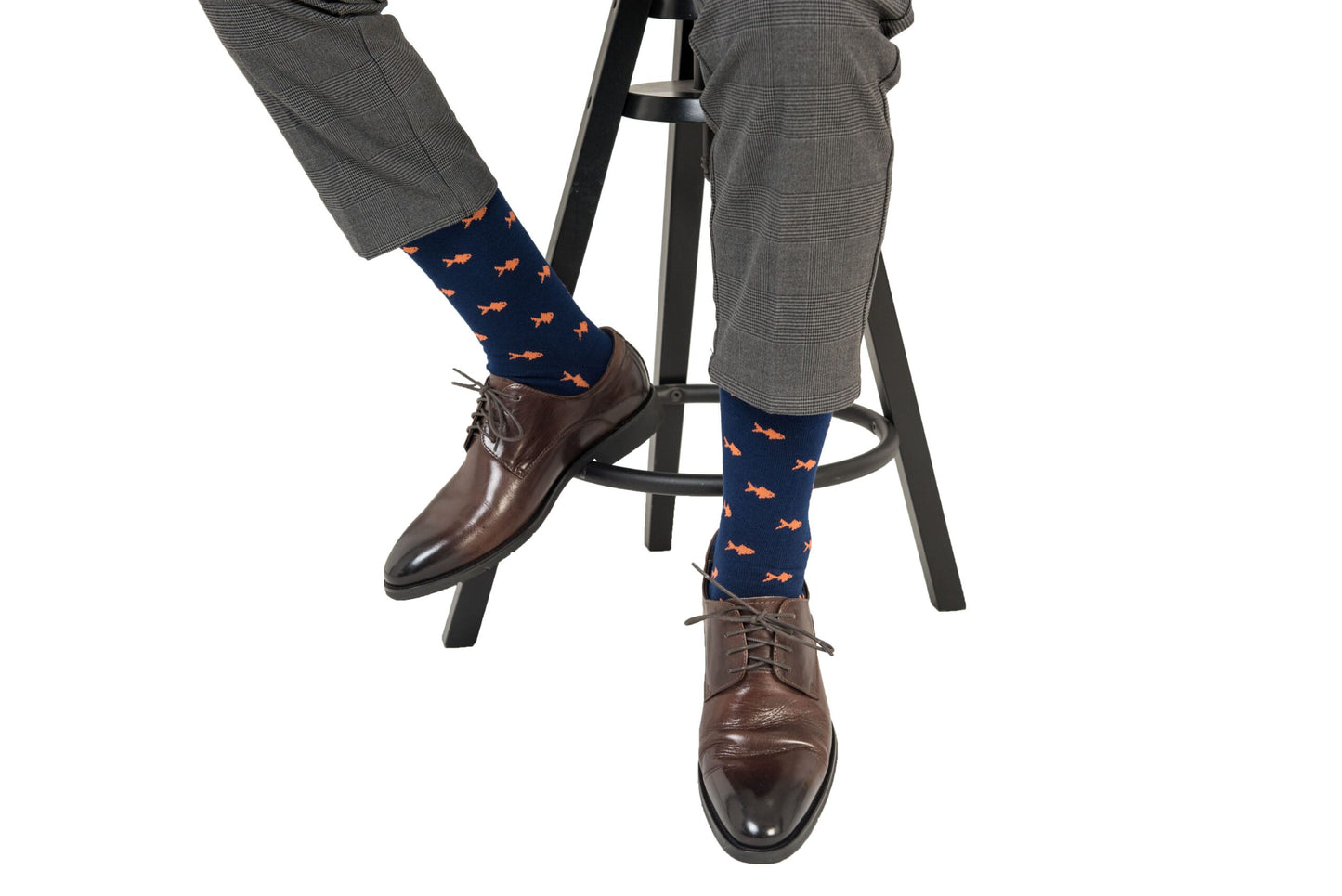 A man sitting on a stool wearing a pair of Gold Fish Socks.