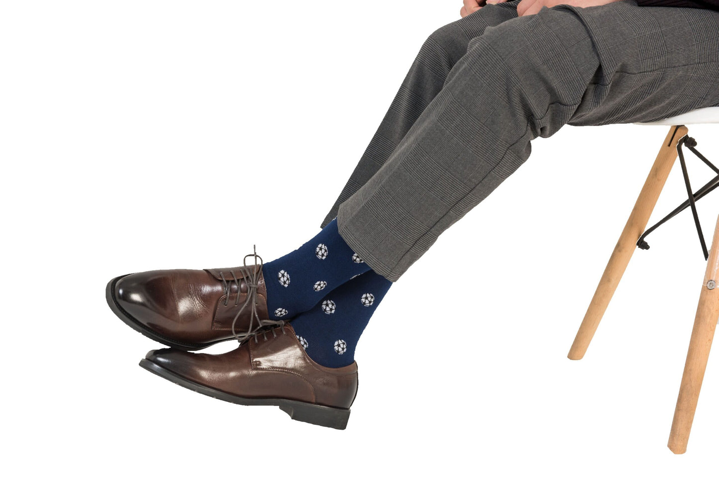 A person wearing brown dress shoes, Soccer Socks, and gray pants sits on a chair with wooden legs, exuding goal-worthy comfort in every step.