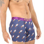 A man wearing Rocket Underwear, featuring blue boxer briefs adorned with a rocket ship print and a purple waistband, stands against a white background. His torso and arms are tattooed. The cosmic design of the Rocket Underwear adds an extra layer of comfort to the vibrant ensemble.