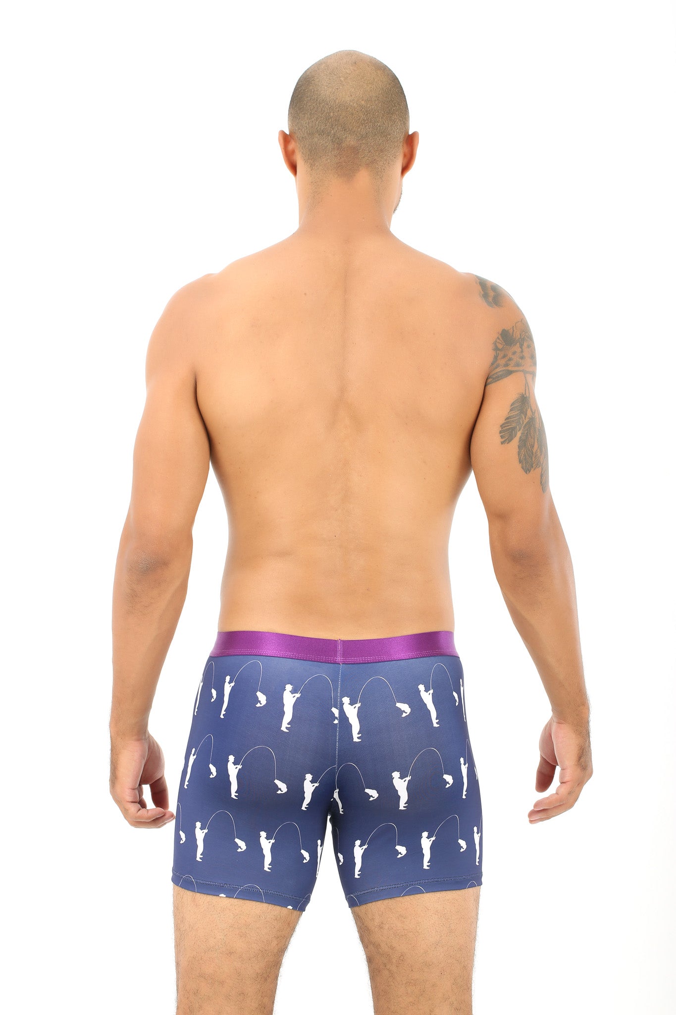 A man stands with his back to the camera, exuding comfort in Fisherman Underwear - patterned navy boxer briefs featuring a striking purple waistband that catches the eye.