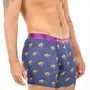 A person wearing Racing Horse Underwear in purple, featuring a playful pattern of grazing camels, stands against a plain white background.