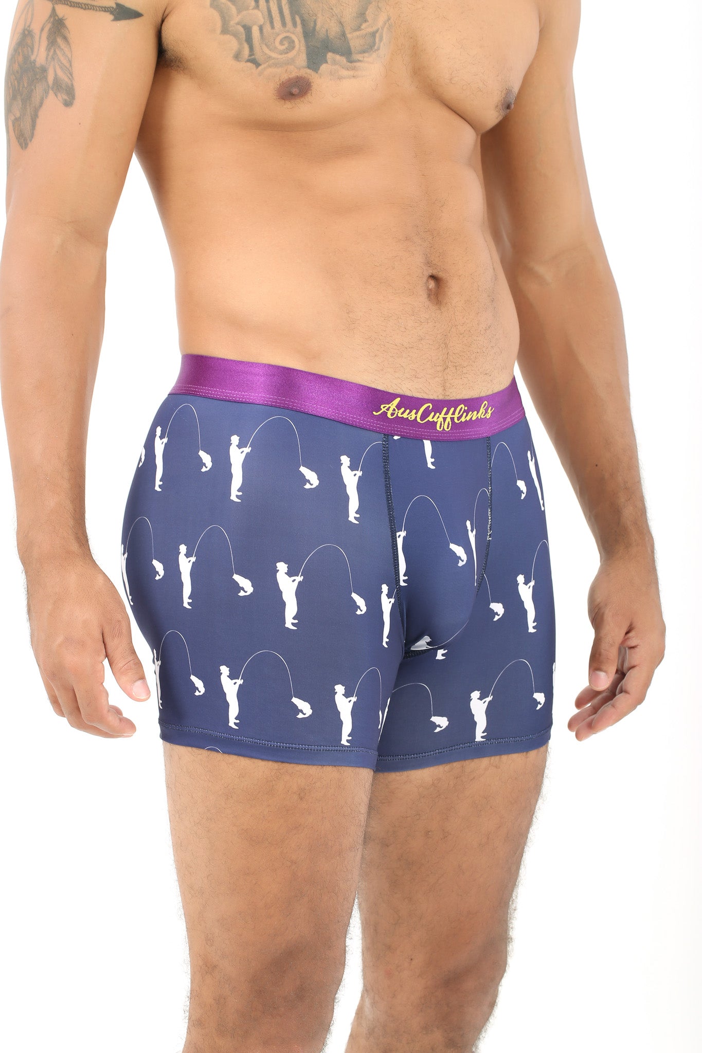 A man is sporting the Fisherman Underwear, featuring navy boxer briefs with a purple waistband and white fishing pole patterns, blending comfort and style as he dreams of the perfect catch.