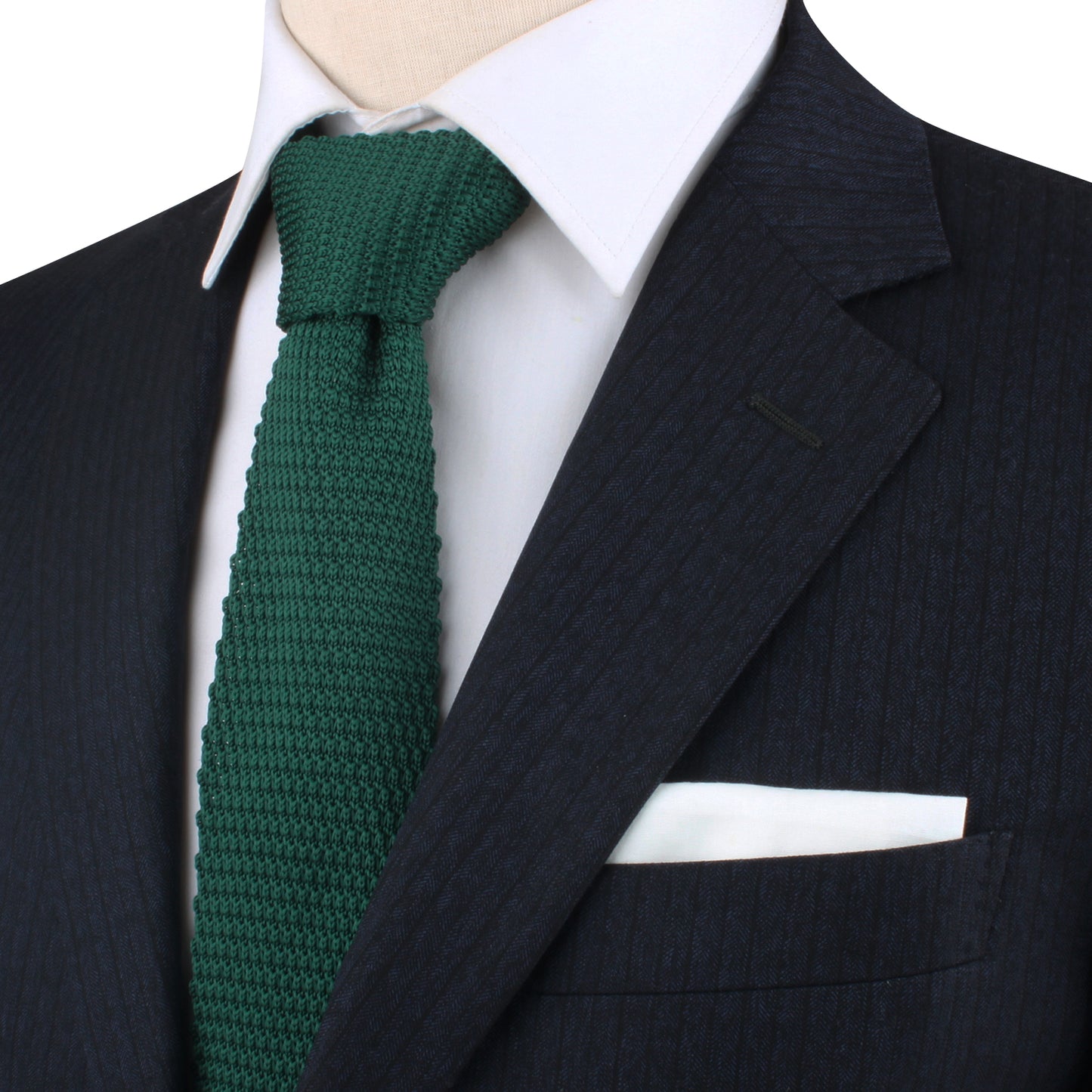 A close-up of a dark suit exudes elegance, complemented by a white shirt and the refreshing Green Knitted Skinny Tie, featuring a crisp white pocket square.