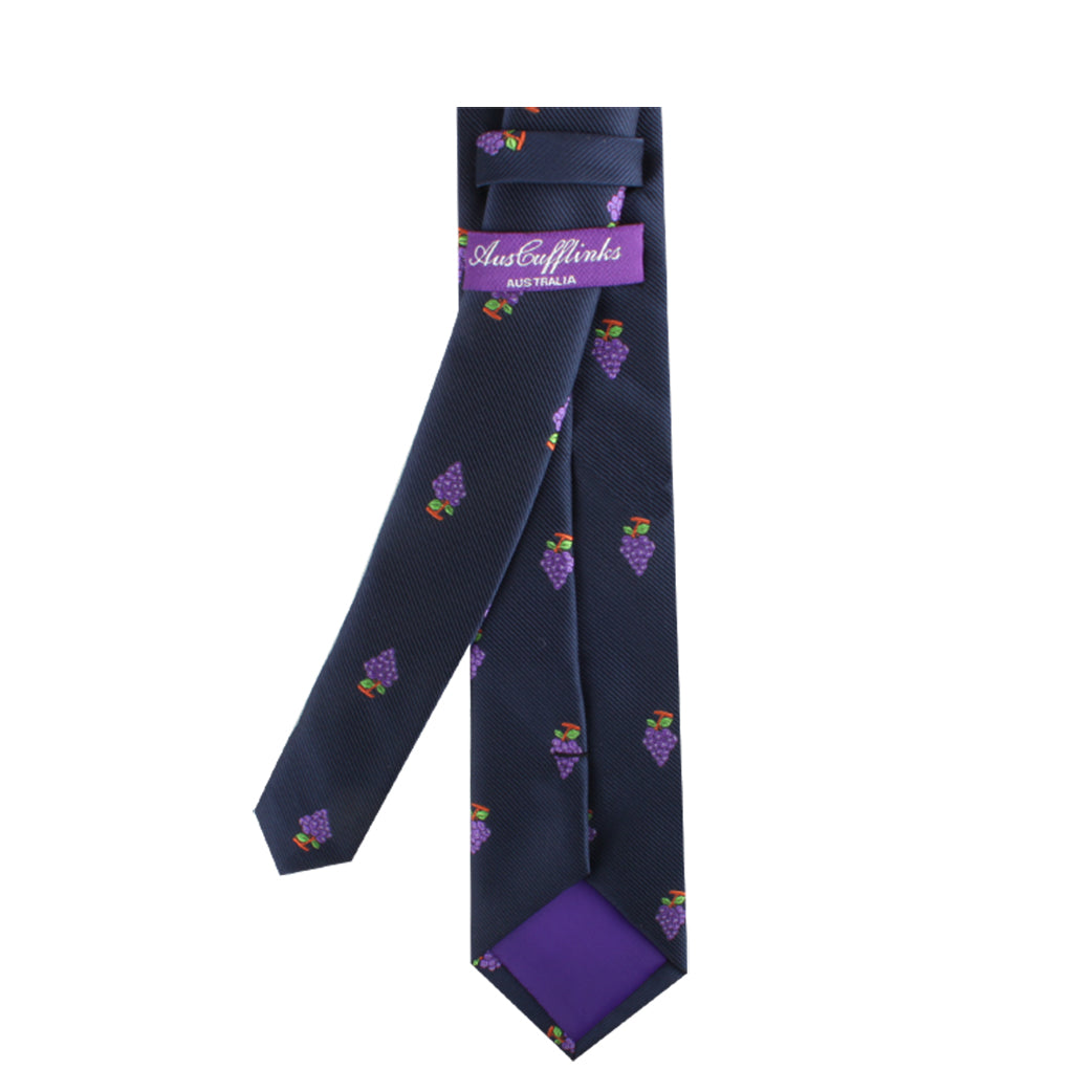 Introducing the Grapes Skinny Tie, a dark blue necktie that exudes vineyard sophistication with its pattern of small grape bunches and is complemented by a rich purple lining. A label proudly declares "AustCufflinks Australian.