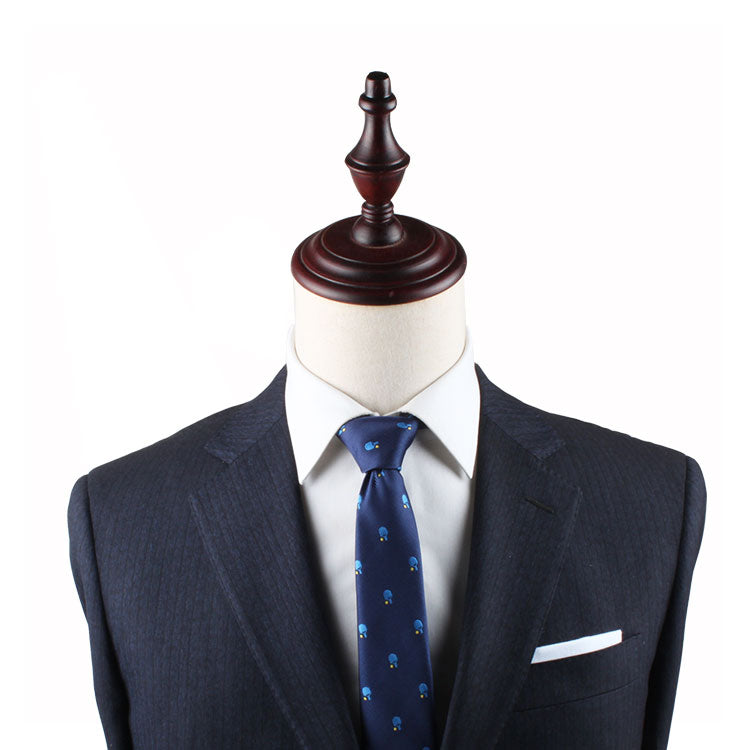 A mannequin dressed in a dark tailored suit with a white dress shirt and a Table Tennis Skinny Tie exudes refined charm, topped with a wooden finial where the head would be.