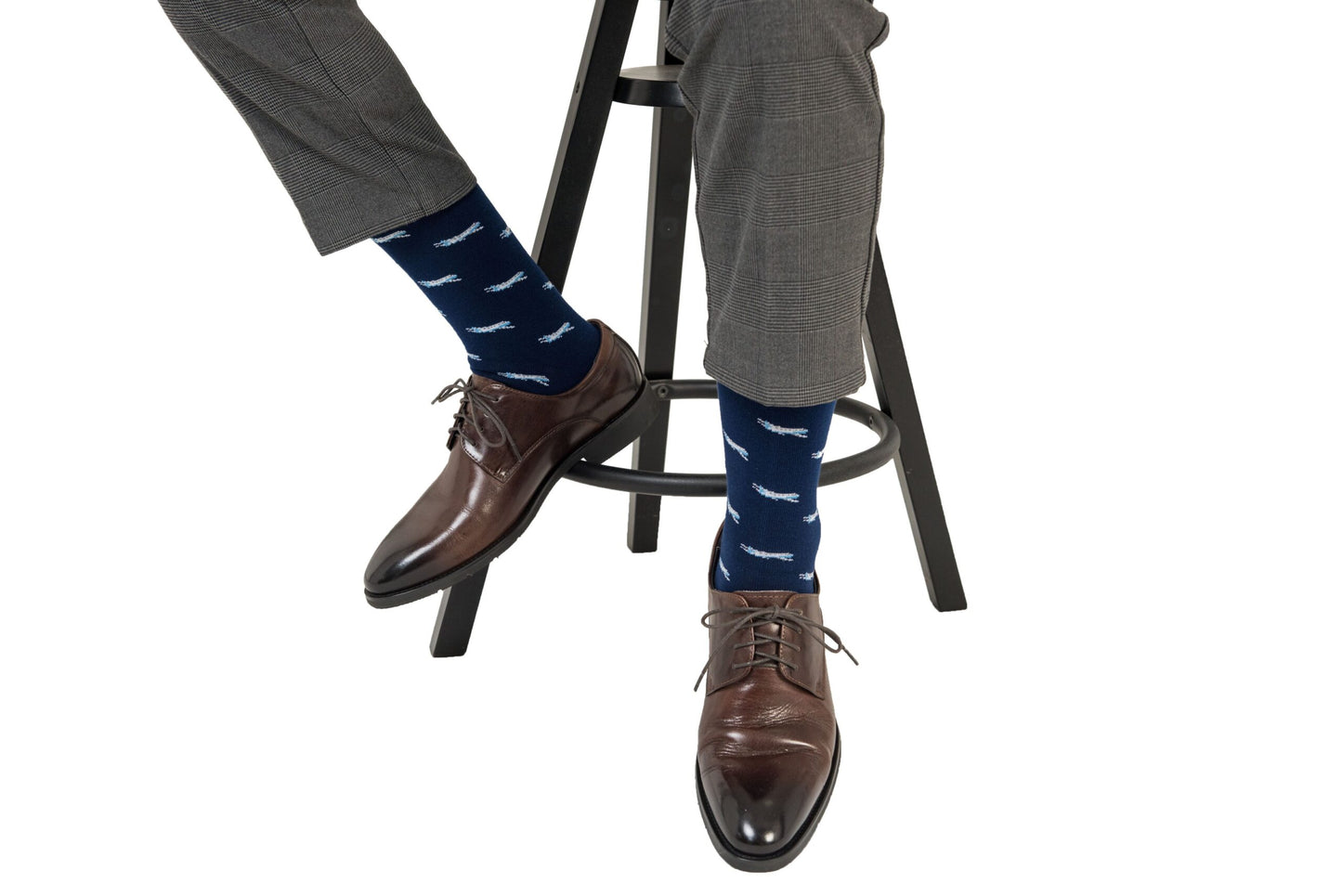 Description: A man sitting on a stool wearing a pair of Aeroplane Socks.