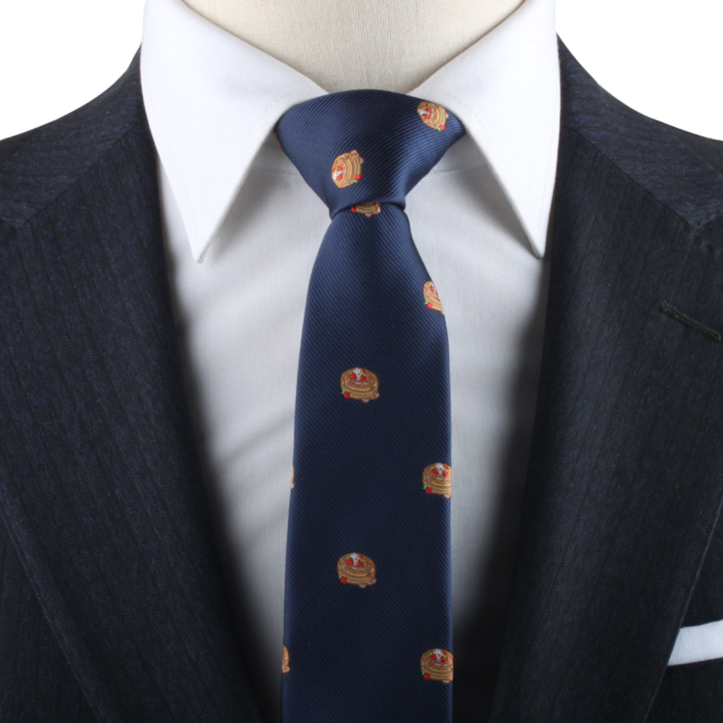 Navy blue Pancakes Skinny Tie with emblem patterns on a mannequin dressed in a white shirt and suit jacket.