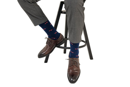 A man showcasing his impressive Racing Car Socks game while sitting on a stool wearing a pair of navy socks.