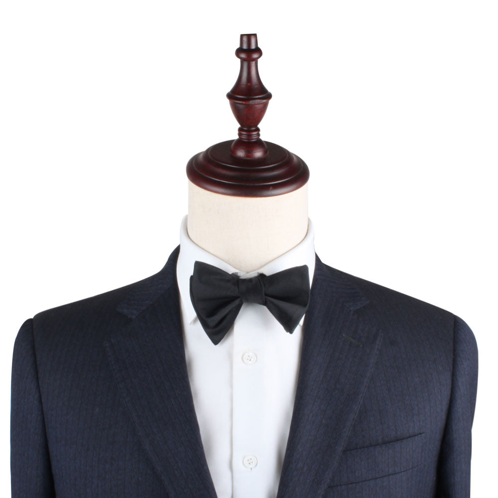 Mannequin dressed in a dark suit jacket, white dress shirt, and a Silk Black Self Tie Bow Tie exudes a timeless elegance.