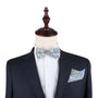 A mannequin showcases an elegant dark pinstripe suit jacket paired with a crisp white shirt, accentuated by the intricate design of a Blue Paisley Bow Tie and a matching pocket square, epitomizing the essence of a true gentleman.