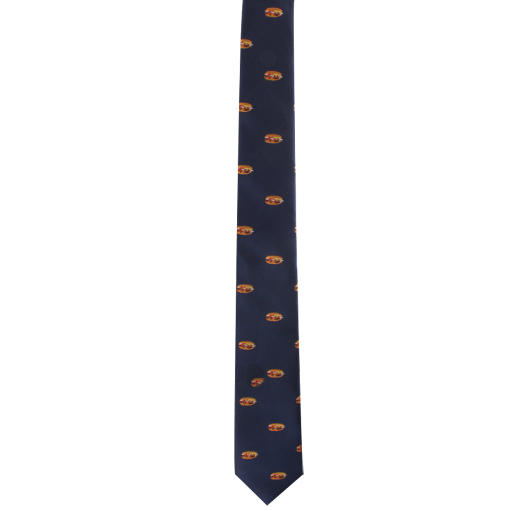 The Pork Roll Skinny Tie features a dark blue color adorned with a repeating pattern of small, circular orange and yellow motifs, exuding a modern charm.