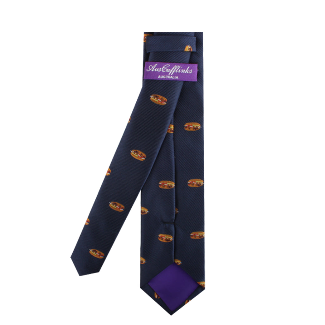 The "Pork Roll Skinny Tie" in navy blue is adorned with small circular patterns and features a purple label reading "Astor&Flanks AUSTRALIA." This tie, exuding modern charm, also has a purple lining at the narrow end.