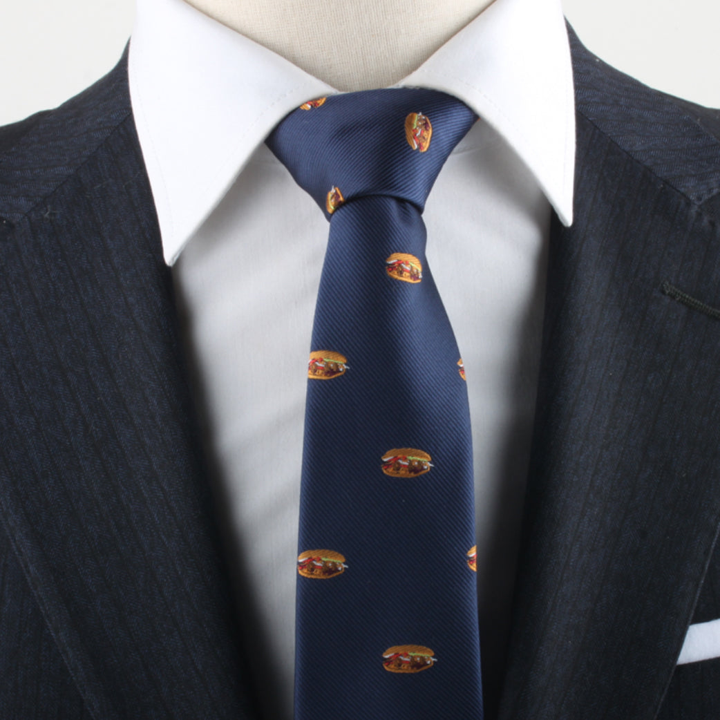 A close-up of a person wearing a dark pinstripe suit, white dress shirt, and the Pork Roll Skinny Tie exudes modern charm, blending sophisticated style with a subtle nod to comfort food.