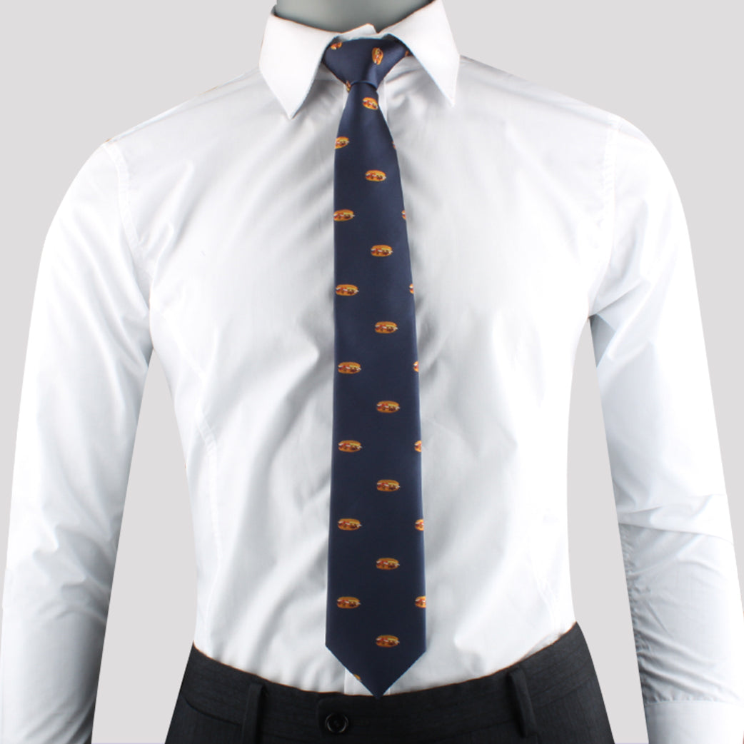 A mannequin wearing a white collared dress shirt paired with the Pork Roll Skinny Tie, featuring a repeating pattern in dark blue, and dark-gray trousers exudes modern charm against a plain light gray background.