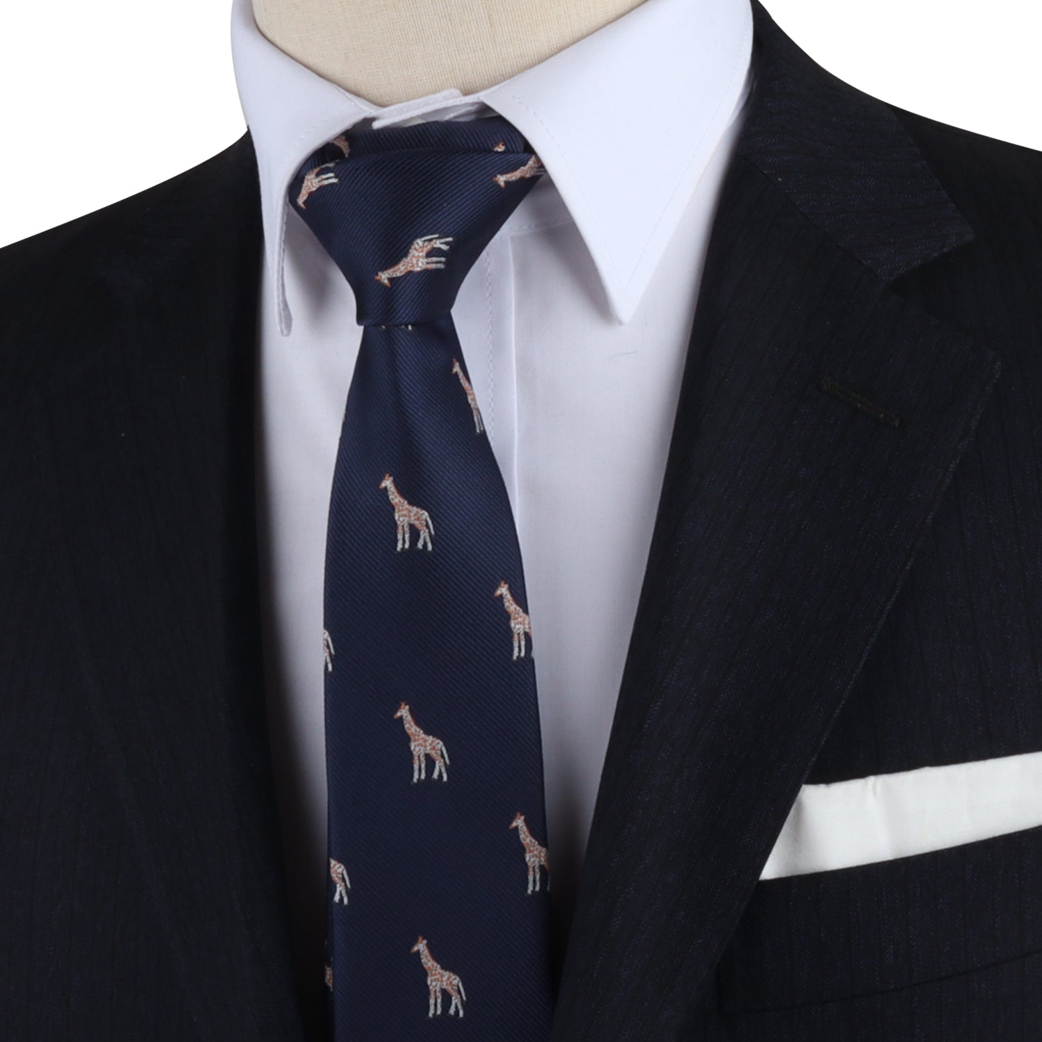 Close-up of a person wearing a dark suit with a white dress shirt and the Giraffe Skinny Tie, which features a pattern of small giraffes and adds a touch of safari sophistication. A white pocket square is visible in the suit pocket.