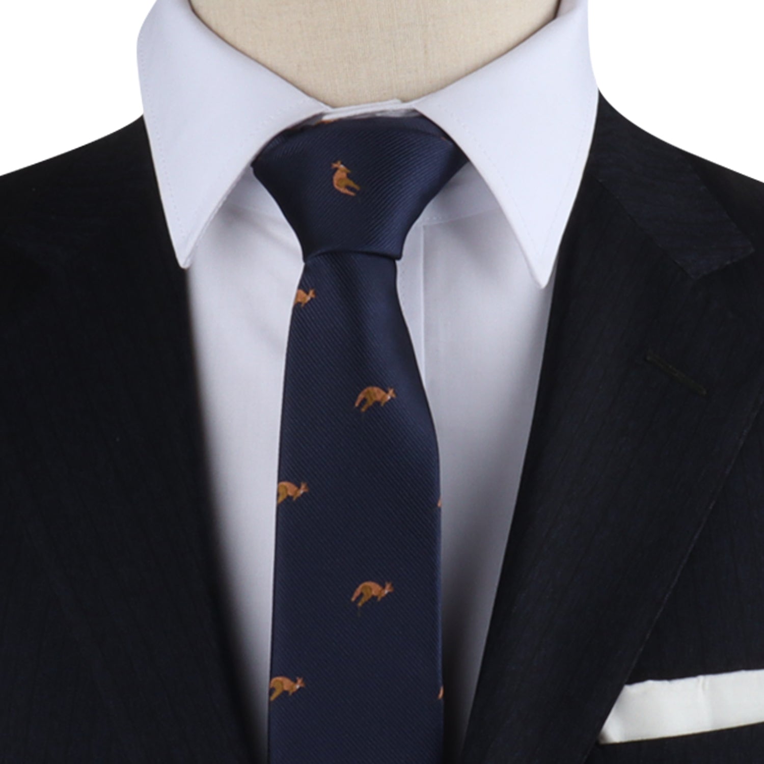 Close-up of a person in a dark suit and white shirt, wearing the Kangaroo Skinny Tie—a navy blue tie adorned with small golden animal motifs—and a white pocket square—unmatched elegance at its finest.