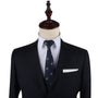 The mannequin presents an effortlessly harmonized look, dressed in a dark suit, white shirt, and the Musical Note Skinny Tie in patterned navy, complemented by a crisp white pocket square.