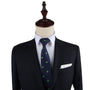 A bold statement of style, this dark suit and tie ensemble on the mannequin features the Weed Skinny Tie, a navy blue tie adorned with an intricate green leaf pattern.