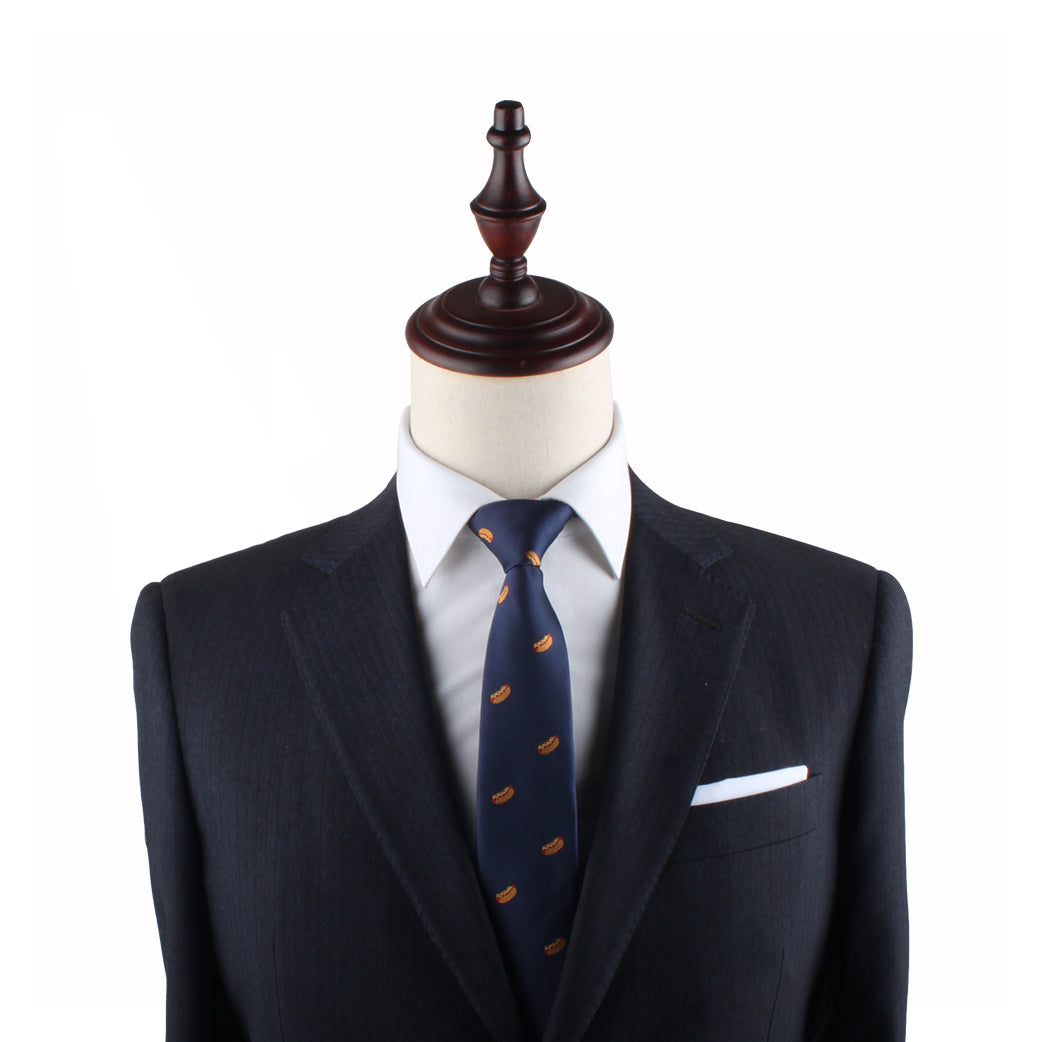 A headless mannequin exudes charisma, dressed in a dark suit with a white shirt, complemented by the Hotdog Skinny Tie featuring small motifs and a crisp white pocket square.