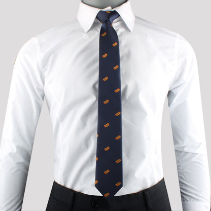 A person exuding charisma in a white dress shirt, dark trousers, and a navy blue Hotdog Skinny Tie with a repeating orange pattern.