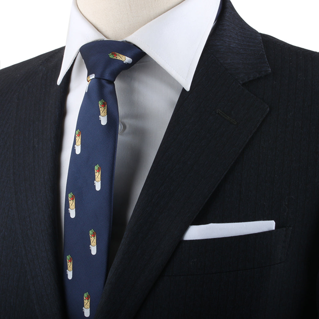 Close-up of a person wearing a dark suit, white shirt, and the Kebab Skinny Tie featuring an intricate kebab pattern. A white pocket square is visible in the suit jacket pocket, capturing the essence of refined fashion with a subtle savory touch of personality.