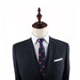 Mannequin exuding elegance, dressed in a dark suit with a white shirt and the Macaroon Skinny Tie featuring red oval patterns.