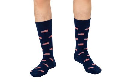 A person is wearing USA Flag Socks in navy blue, featuring small American flag designs with stars and stripes in a subtle yet stylish manner.