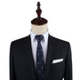 A mannequin dressed in a dark suit with a white dress shirt, a Fisherman Skinny Tie featuring a subtle pattern, and a white pocket square effortlessly compliments its refined look.