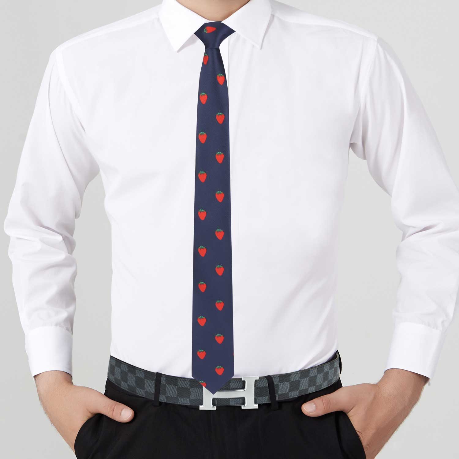 A man in a white dress shirt and black pants showcases the Strawberry Skinny Necktie, adding a fruity charm to his look, complemented by a checkered belt.