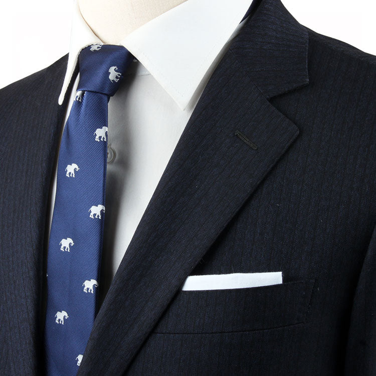 A close-up of a person wearing a dark pinstriped suit, a white dress shirt, and an Elephant Skinny Tie, complemented by a white pocket square.