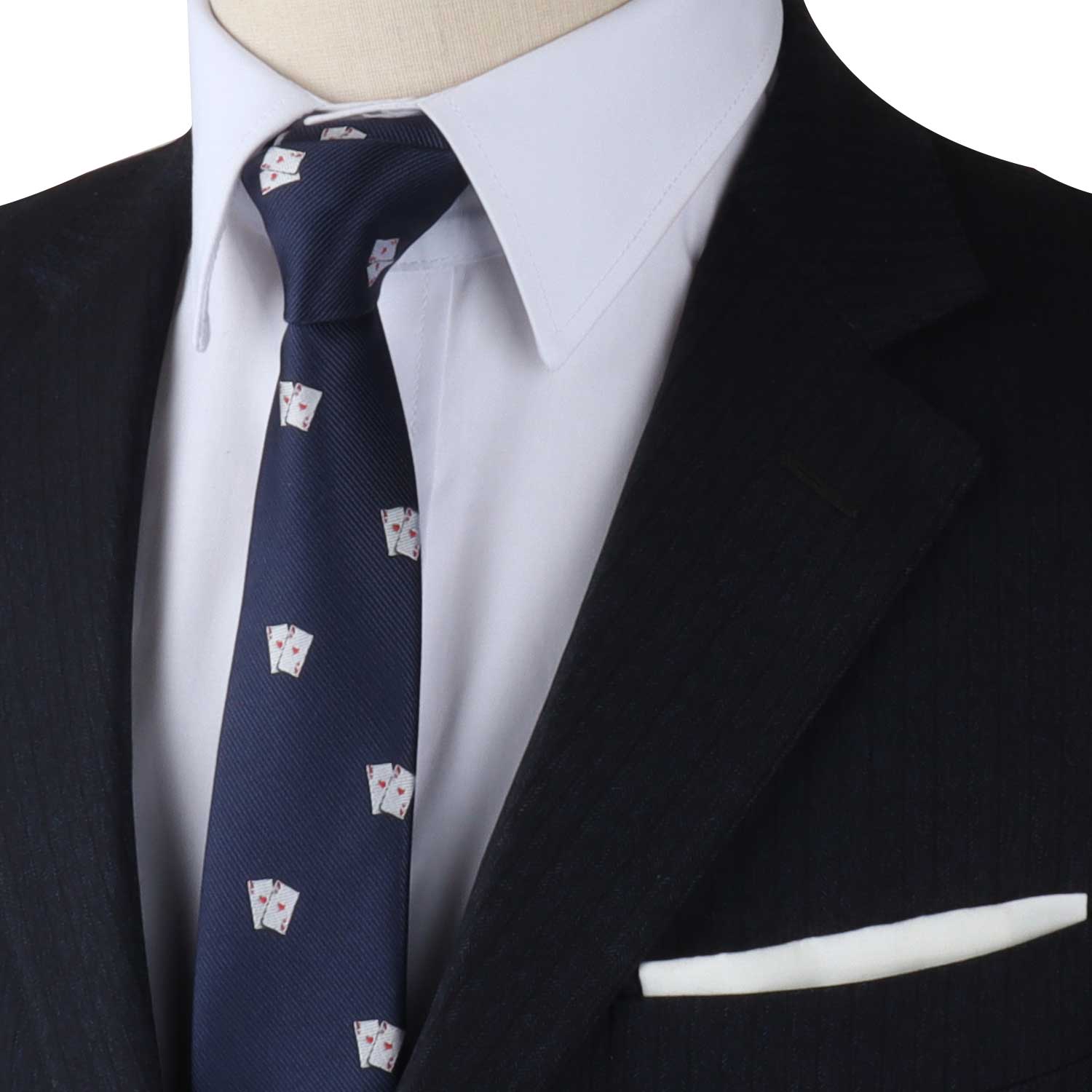 Close-up of a man wearing a black suit, white dress shirt, and the Poker Cards Skinny Tie with playful card designs in navy blue, featuring a white pocket square that elevates your style.