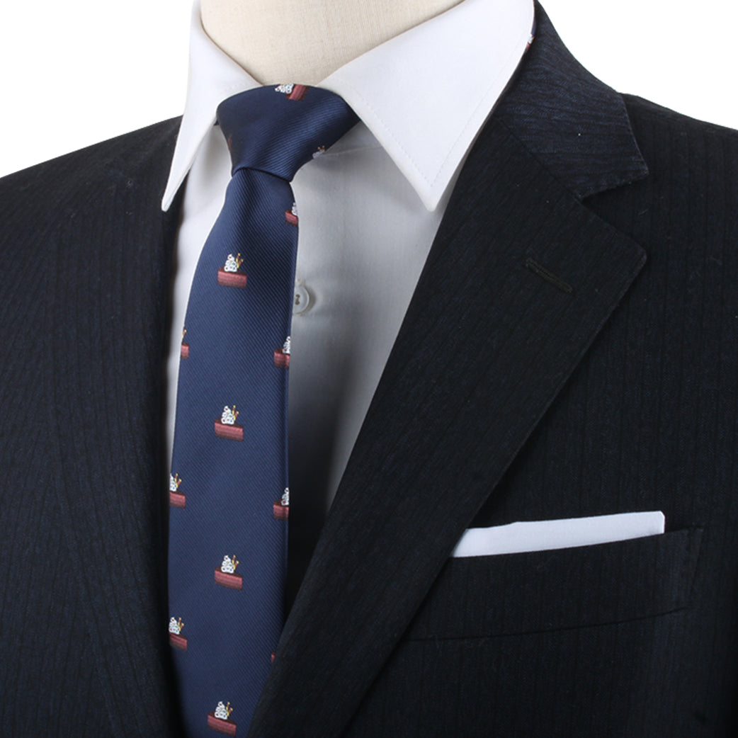 Close-up of a person wearing an elegant dark pinstripe suit, complemented by a white dress shirt and the Cake Skinny Tie, featuring a sweet touch of cactus design. A crisp white pocket square adds the finishing touch to this sophisticated attire.