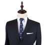 A mannequin displaying a dark suit with a white shirt and the Dice Skinny Tie featuring a light blue pattern exudes an effortless style.