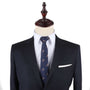 A dark suit paired with the Skateboarder Skinny Tie, featuring subtle patterns, exudes confidence on a mannequin, set against a plain background.