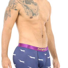 A shirtless man exudes style in Airplane Underwear featuring playful shark prints and a cozy purple waistband, reminiscent of vibrant skies.
