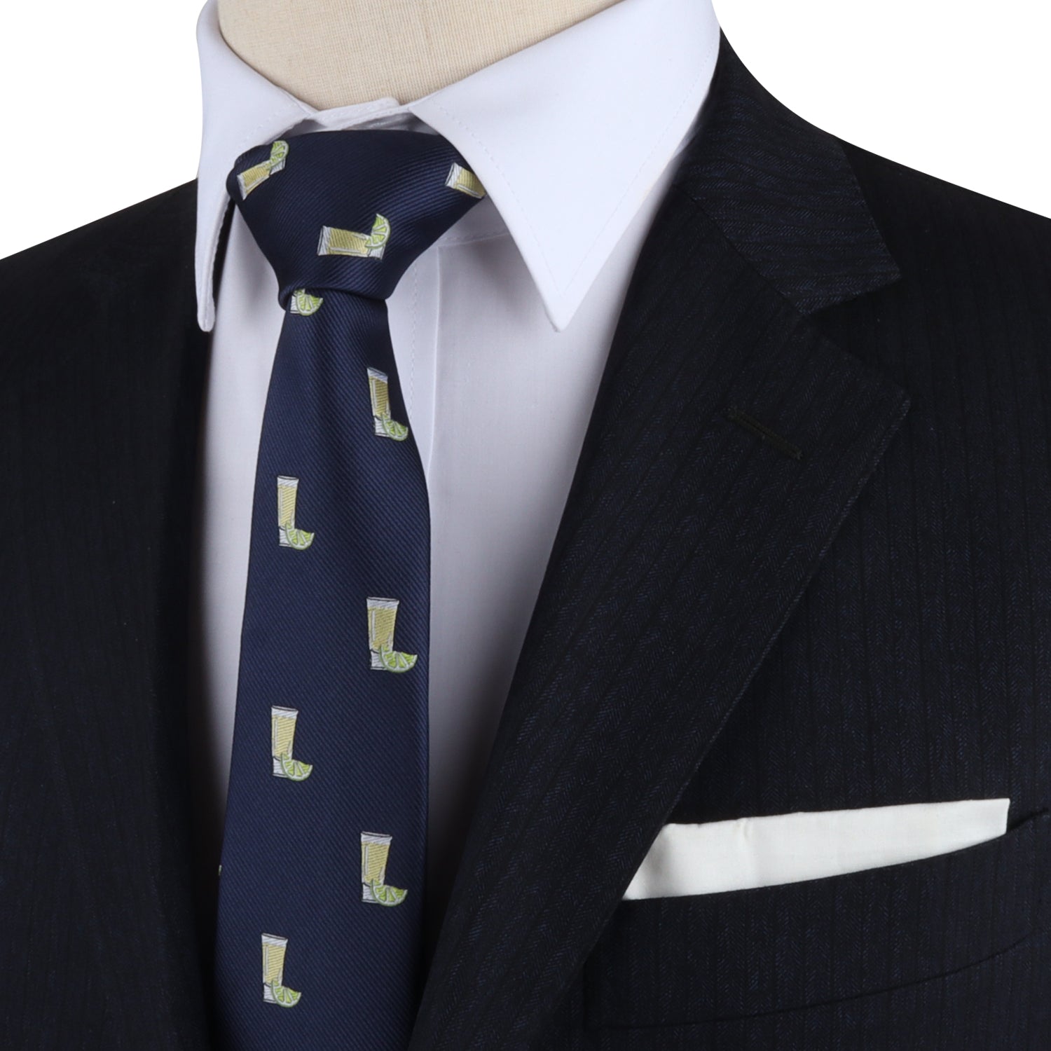 A close-up of a person wearing a black suit, white dress shirt, and the Tequila Skinny Tie featuring green boot prints that add zest to the ensemble. The dapper design is completed with a white pocket square in the suit’s breast pocket.