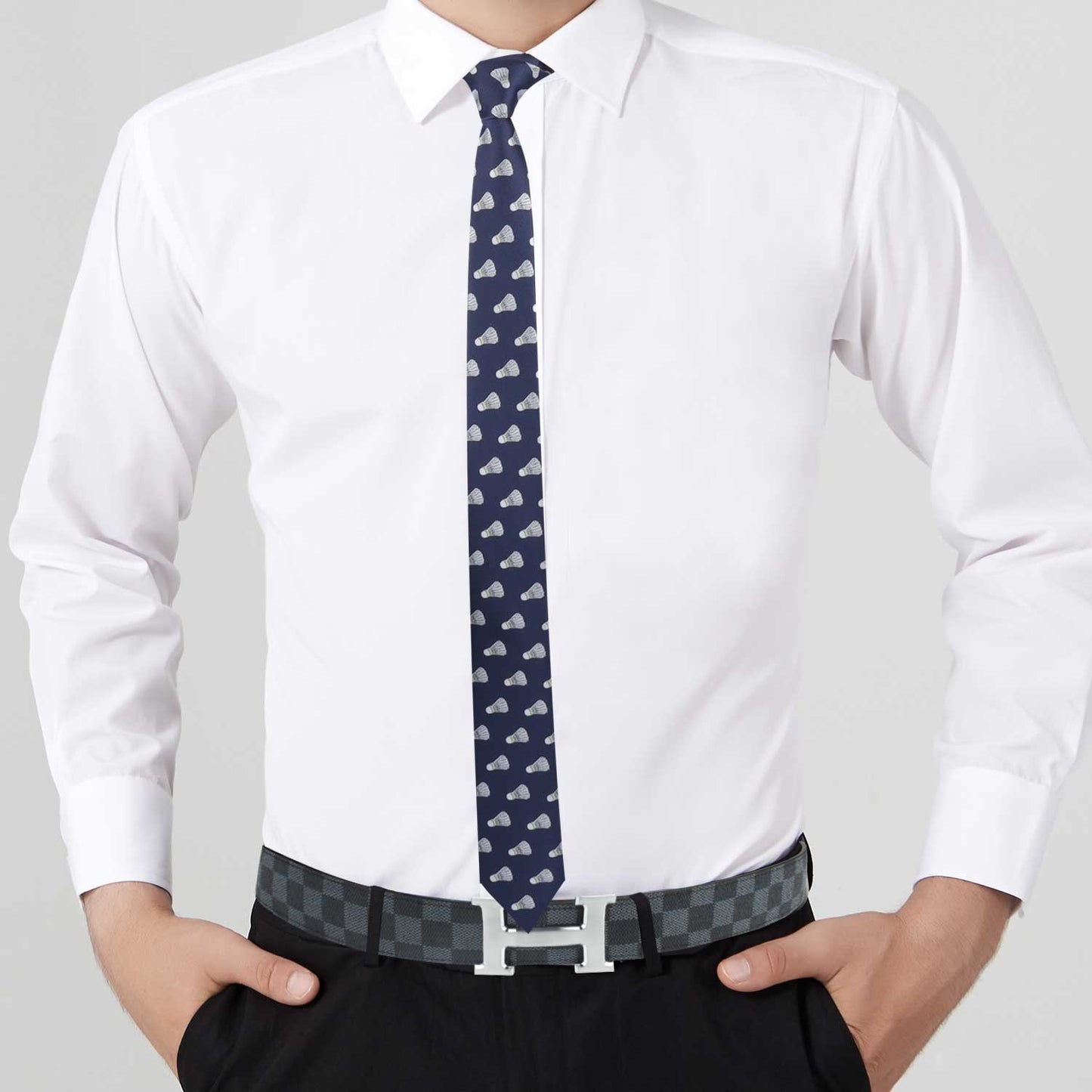 A person serving looks in a white dress shirt, an Athletic Tie, black trousers, and a checkered belt. Their hands are in their pockets.