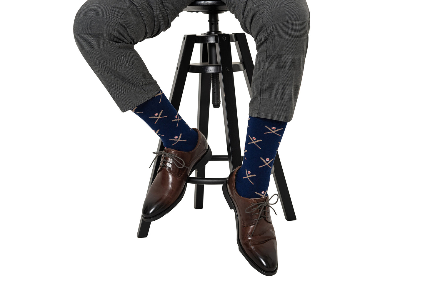 A man sitting on a stool wearing a pair of Crossed Baseball Socks.