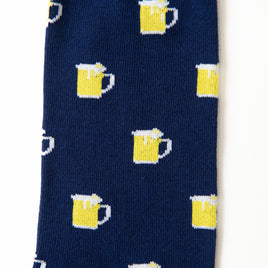 Beer Socks are navy blue with a playful pattern of yellow beer mugs topped with white foam, perfect for beer lovers.