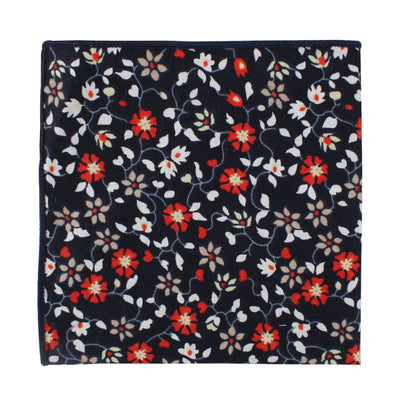 A pocket square with a bold black background adorned with a floral pattern of red, white, and gray amaryllis flowers.